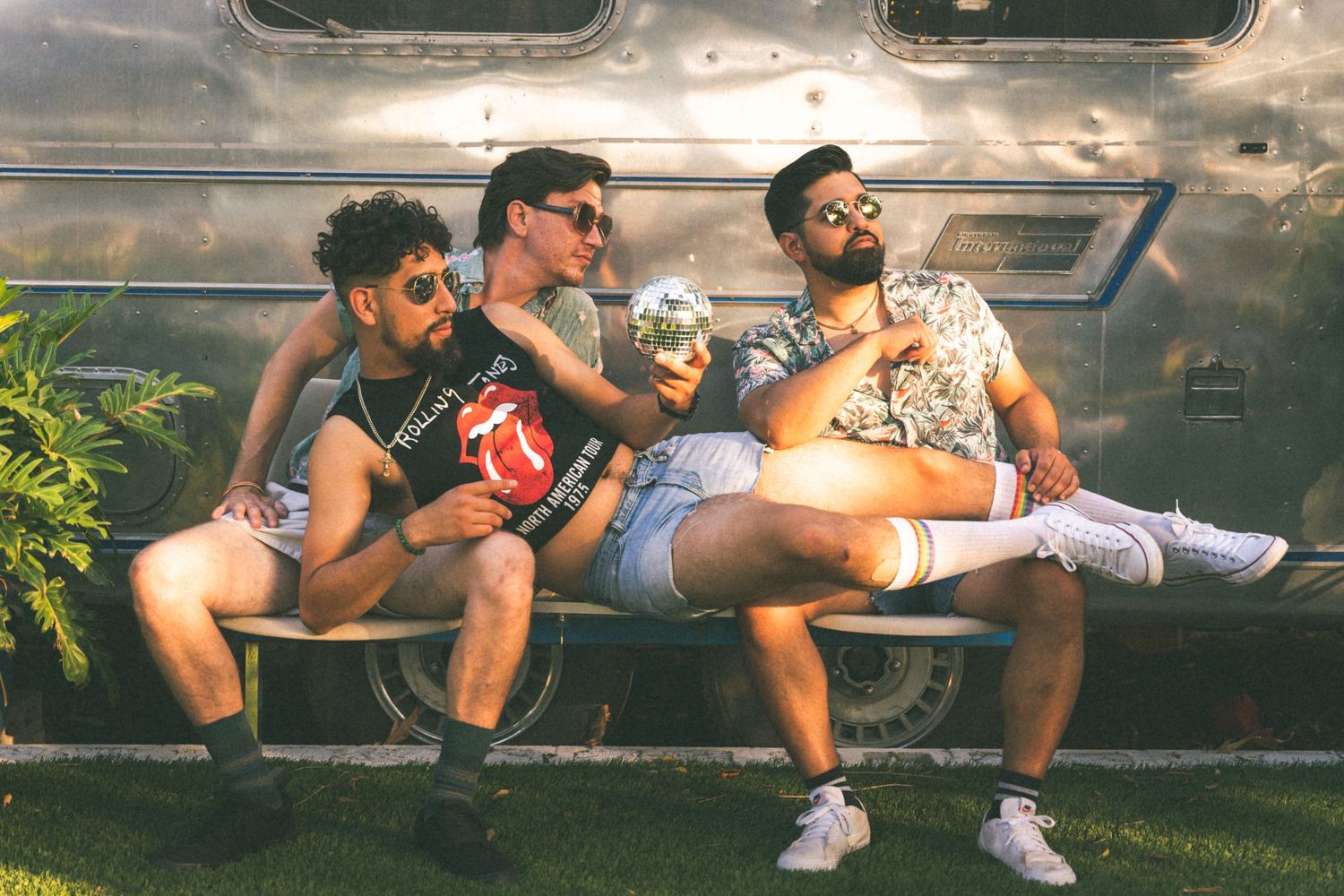 Friends lounging outdoors against metallic surface enjoying casual summer day together.
