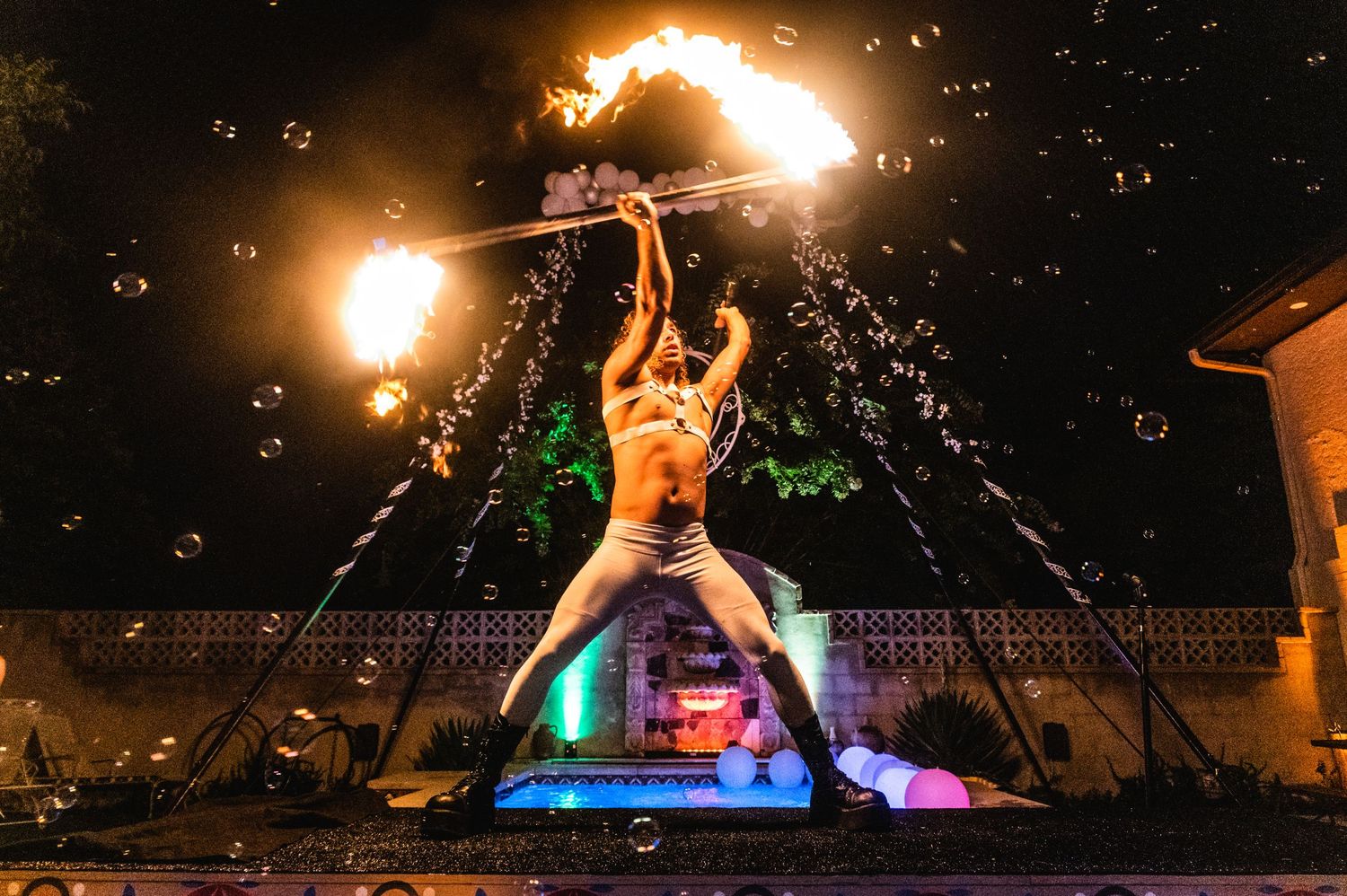 A fire performer creates spectacular light trails against a dark night sky.