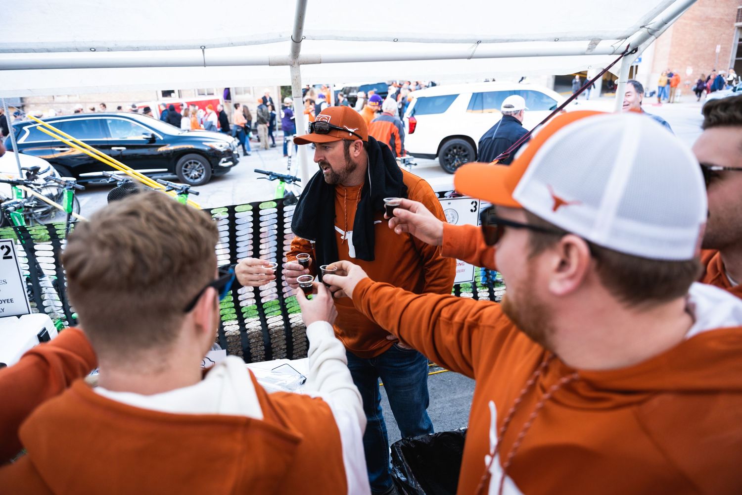Fans in orange team gear celebrate at a tailgate gathering.