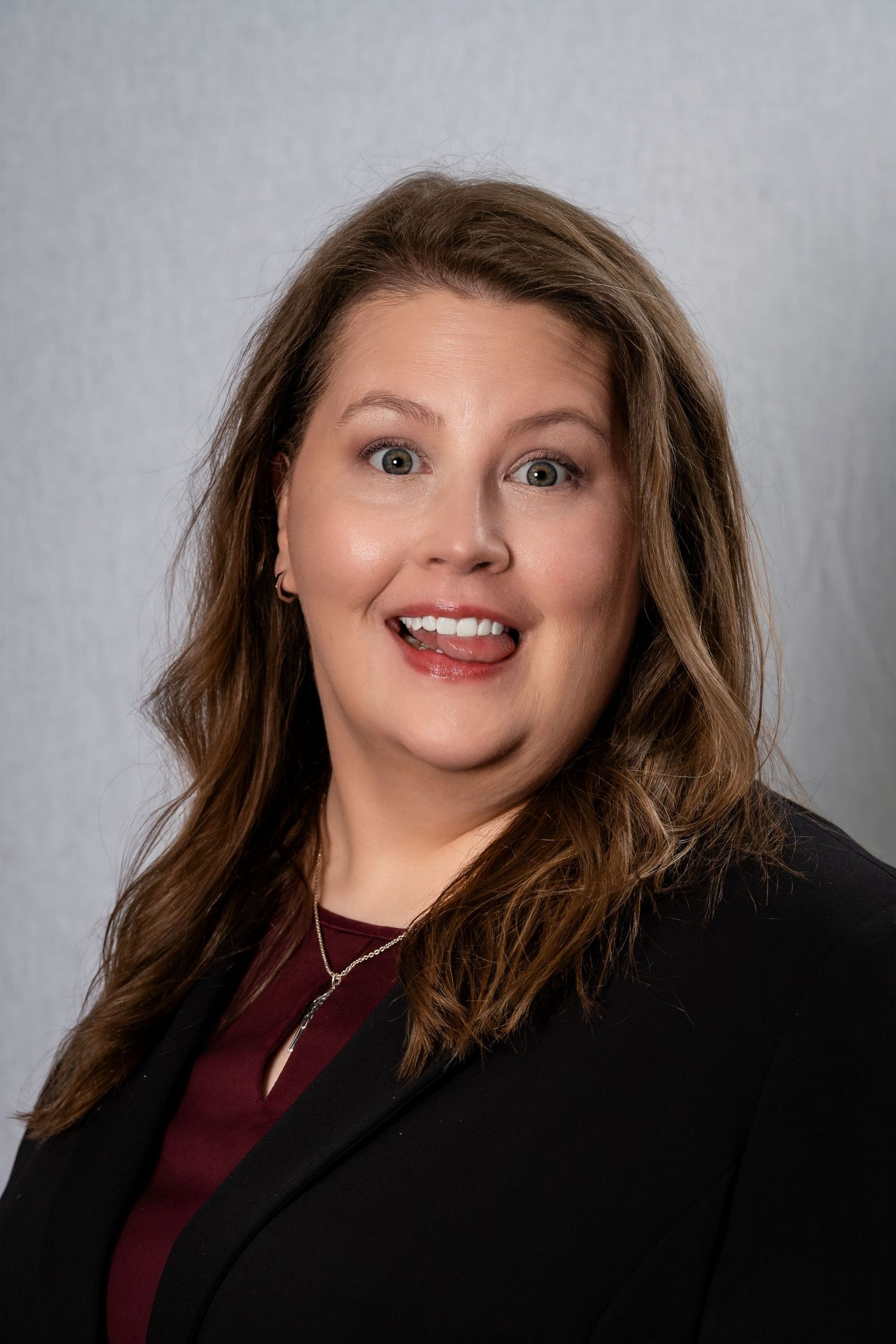 Professional studio portrait of person in business attire with bright smile.