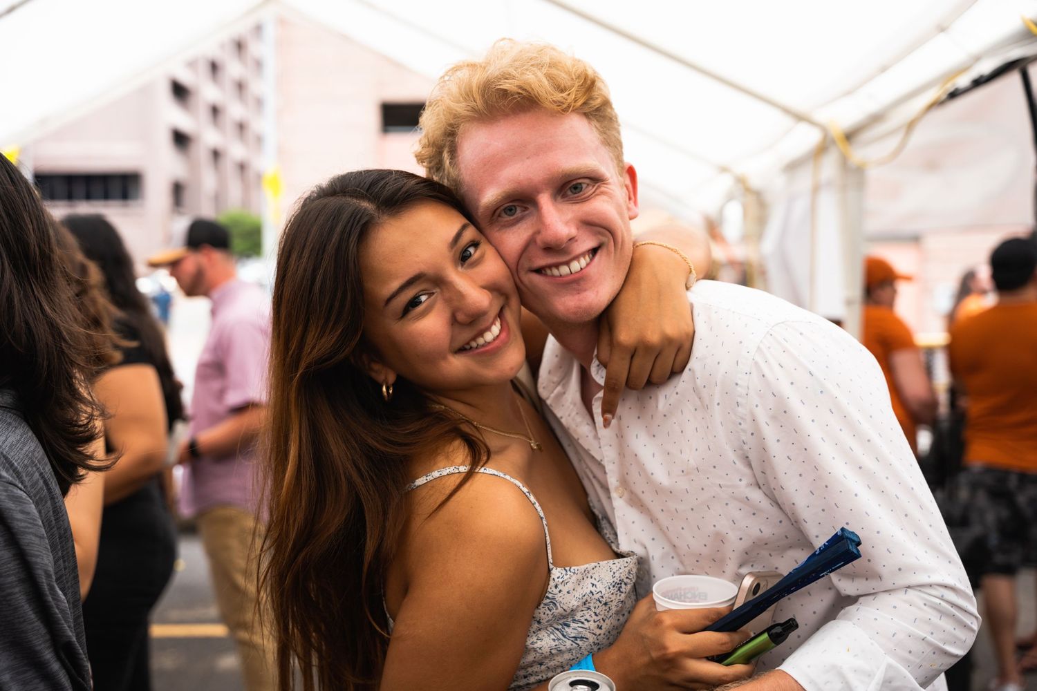Couple sharing a joyful moment while enjoying drinks at an outdoor celebration.