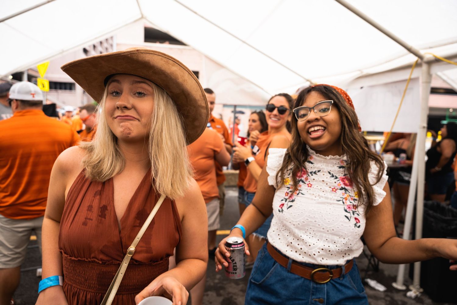 Festival attendees enjoying themselves while dancing under a white tent at an outdoor event.