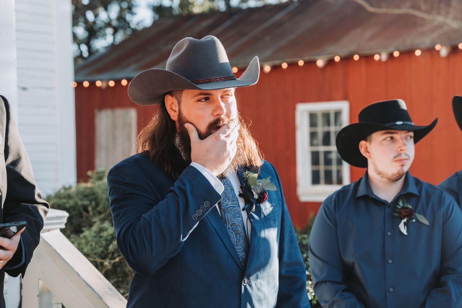 A person in western attire and cowboy hat speaks during an outdoor ceremony.