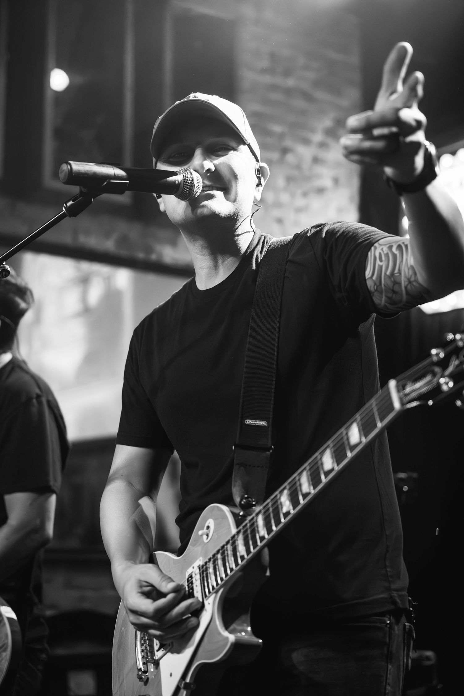 Black and white photo of musician performing with guitar and microphone on stage.