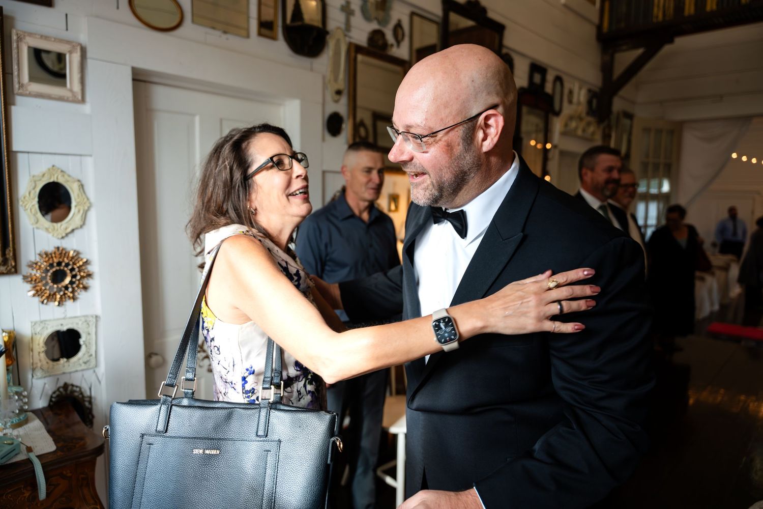 People embracing at an indoor celebration with vintage decor.