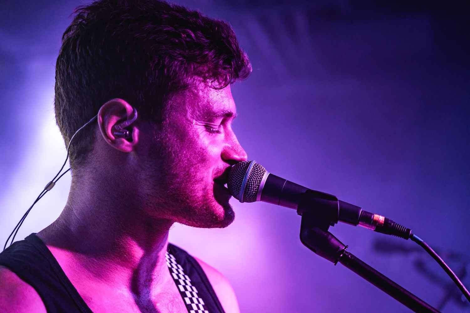 Singer performs into microphone under dramatic purple stage lighting.