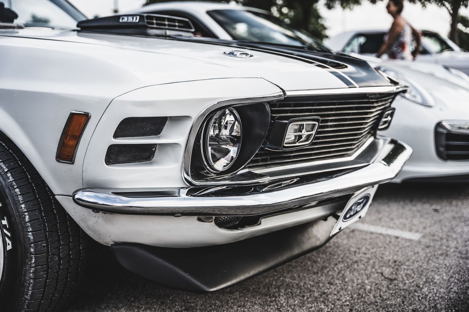 Front end detail of classic Ford Mustang showing chrome grille and headlight.