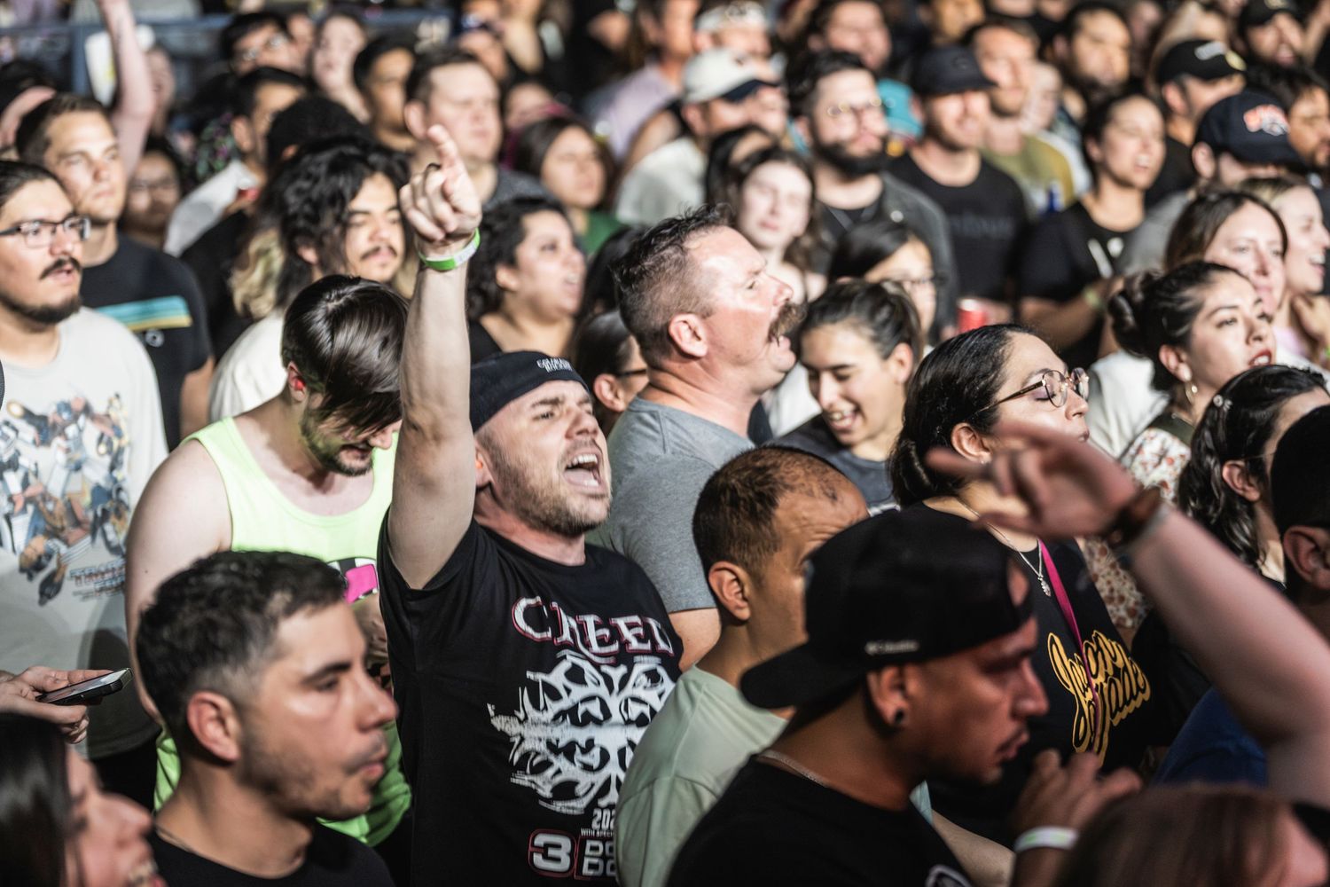 A large crowd of animated concert goers react enthusiastically during a live music performance.