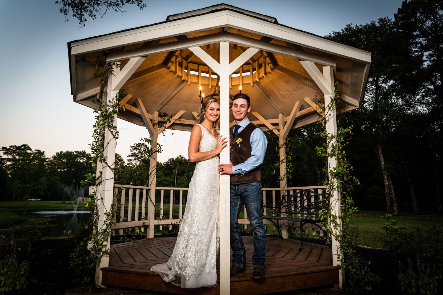 Sunset wedding portrait in decorated gazebo with dramatic lighting.