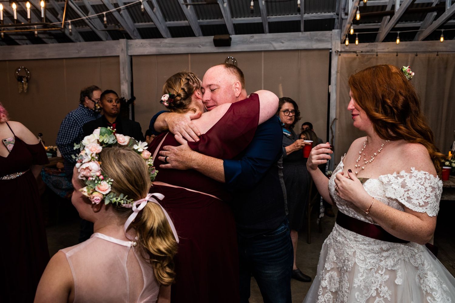 Emotional moment captured during wedding reception with guests embracing on dance floor.