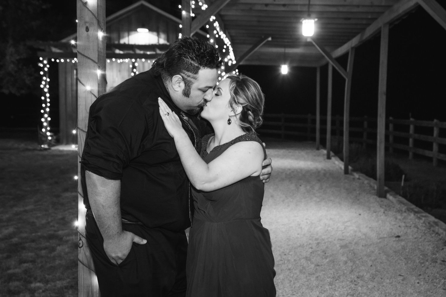 A romantic moment captured between a couple under twinkling lights in black and white.