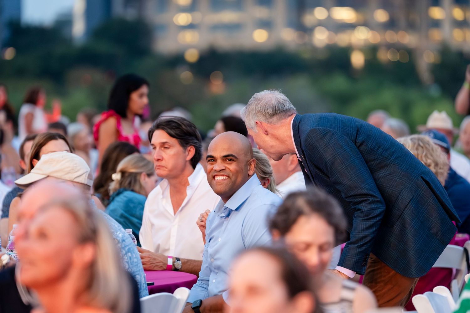 Diverse crowd of people enjoying an outdoor evening event while sitting together in a casual atmosphere.