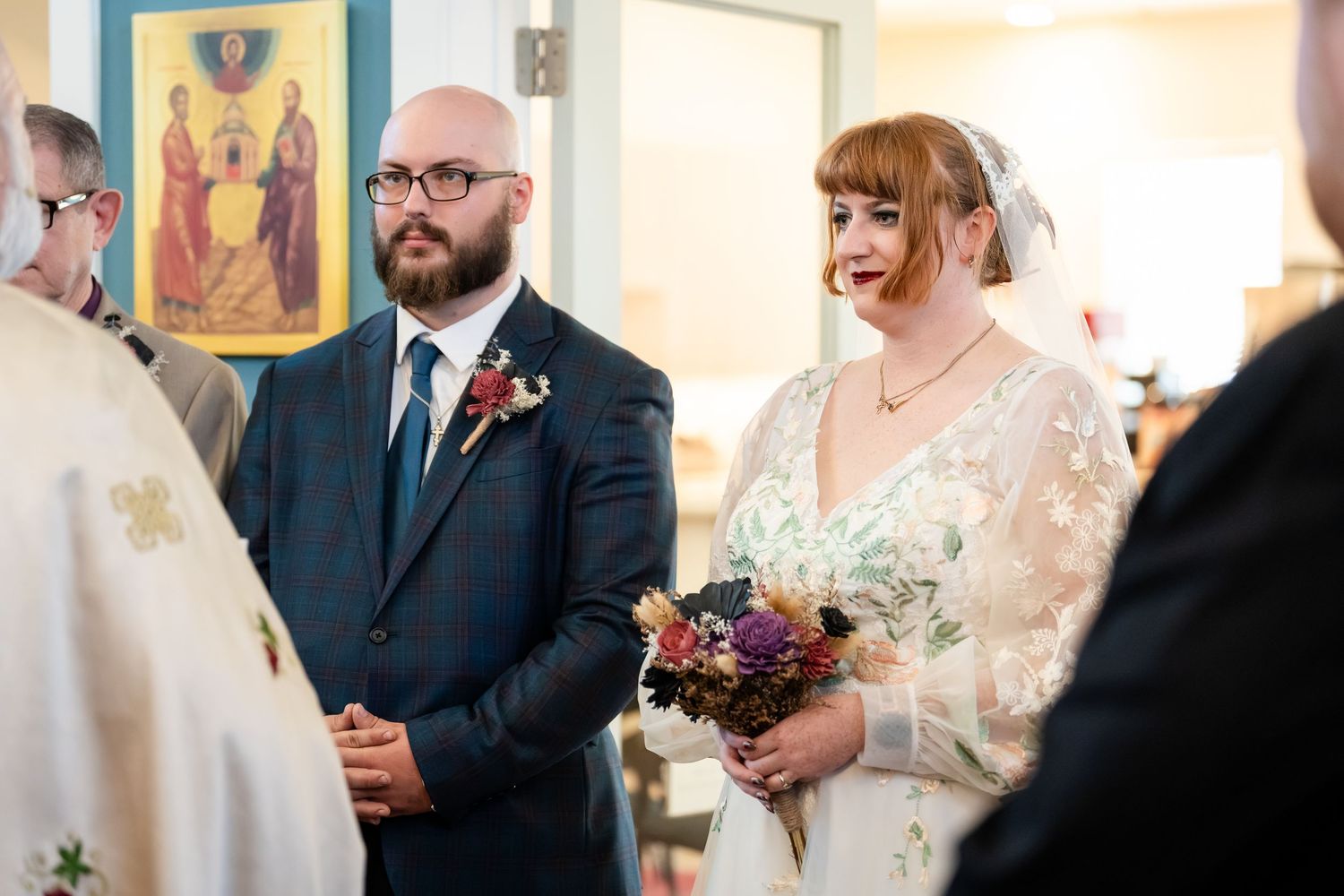 A wedding ceremony takes place in a bright church with religious icons and artwork visible on the walls.