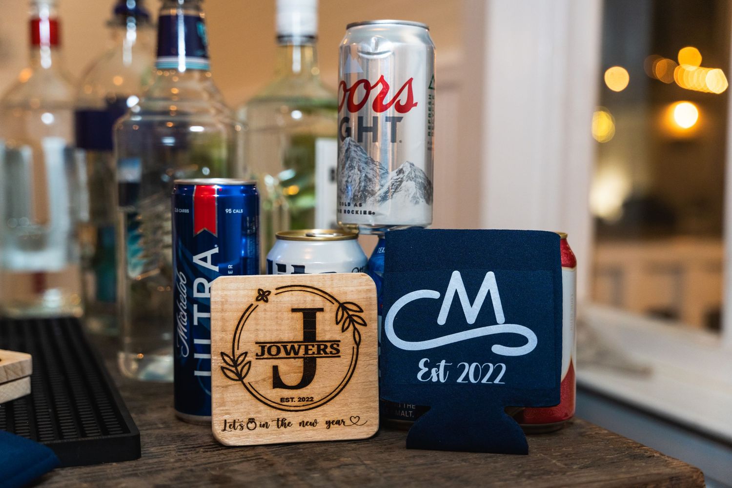 Wedding reception bar setup with personalized wooden coasters and drink koozies.