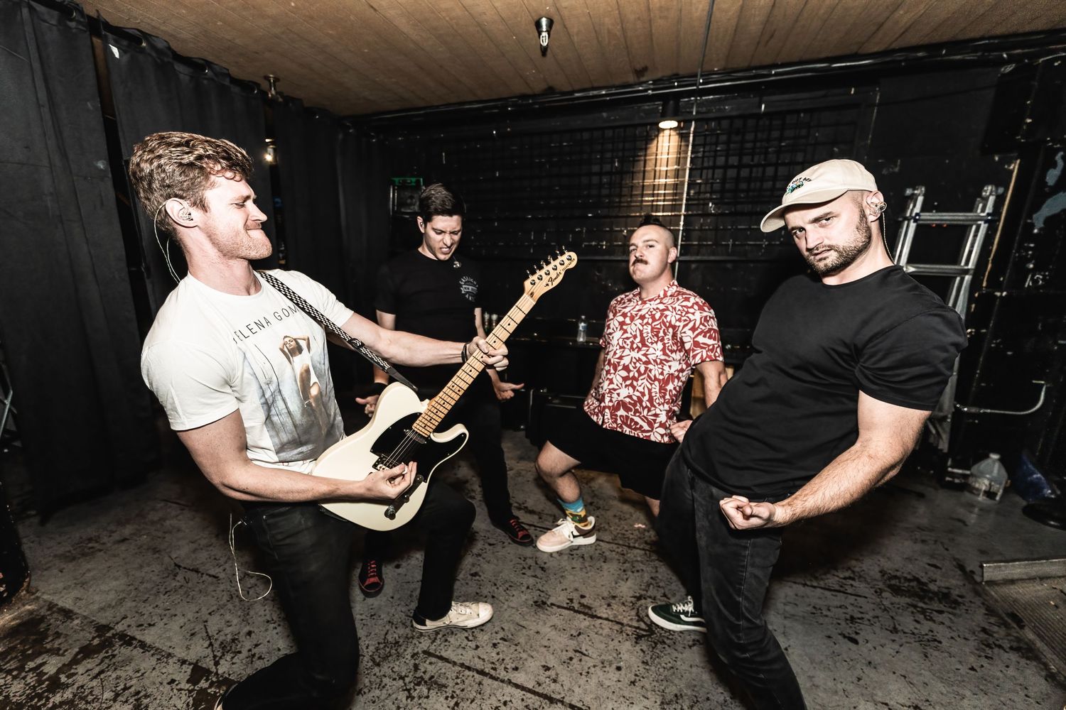 Band members rehearse in a dark basement setting with guitars and musical equipment.