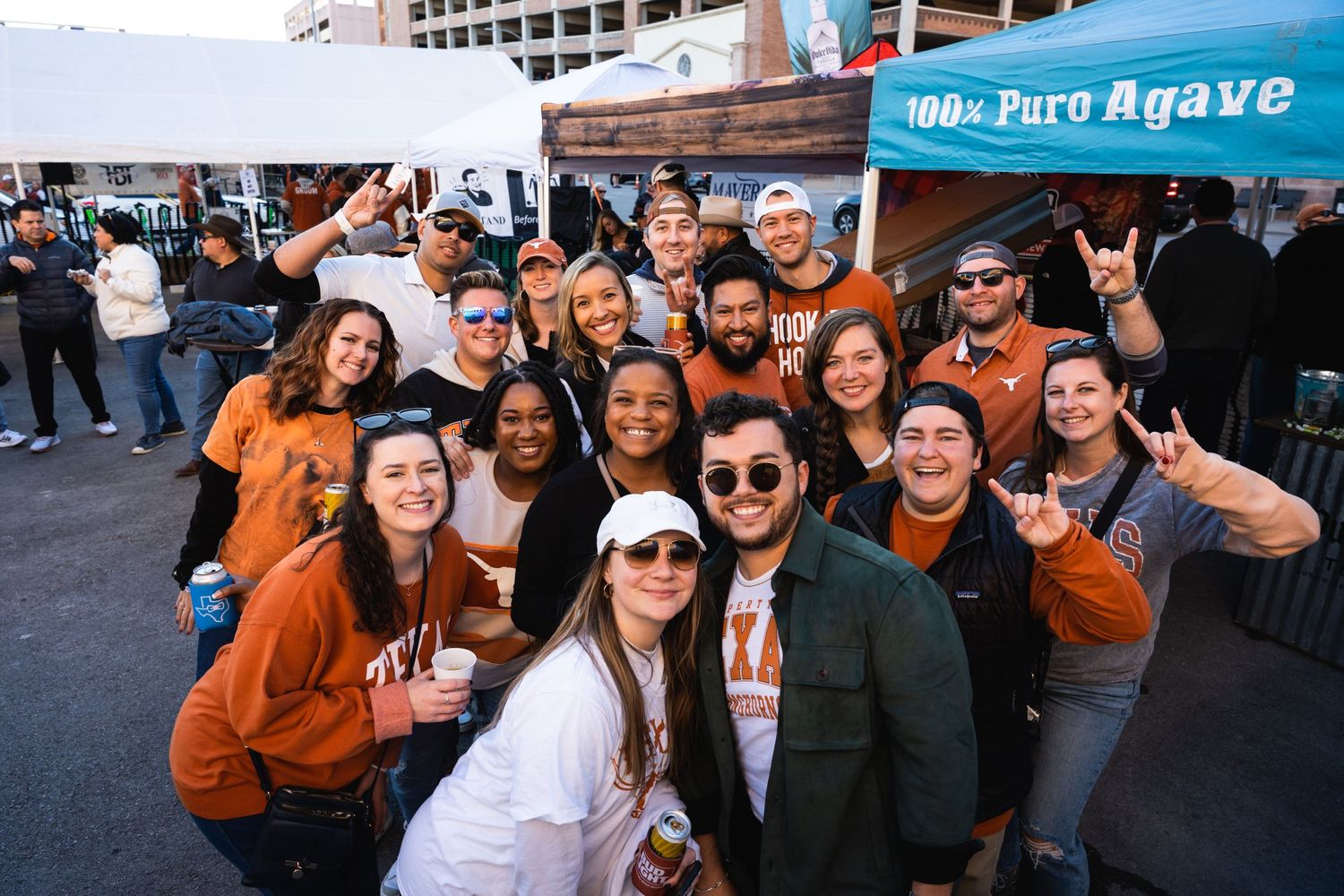 Large group wearing orange shirts poses together at an outdoor event.