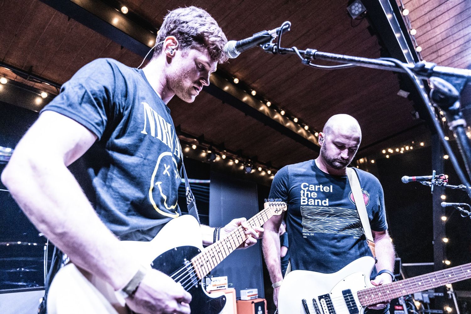 Musicians perform on stage with dramatic lighting and musical equipment.