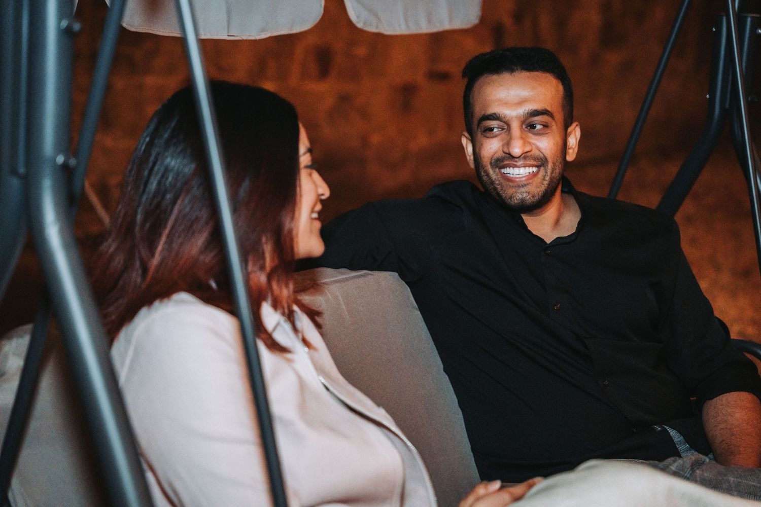 Couple enjoying conversation while relaxing on outdoor furniture at night.
