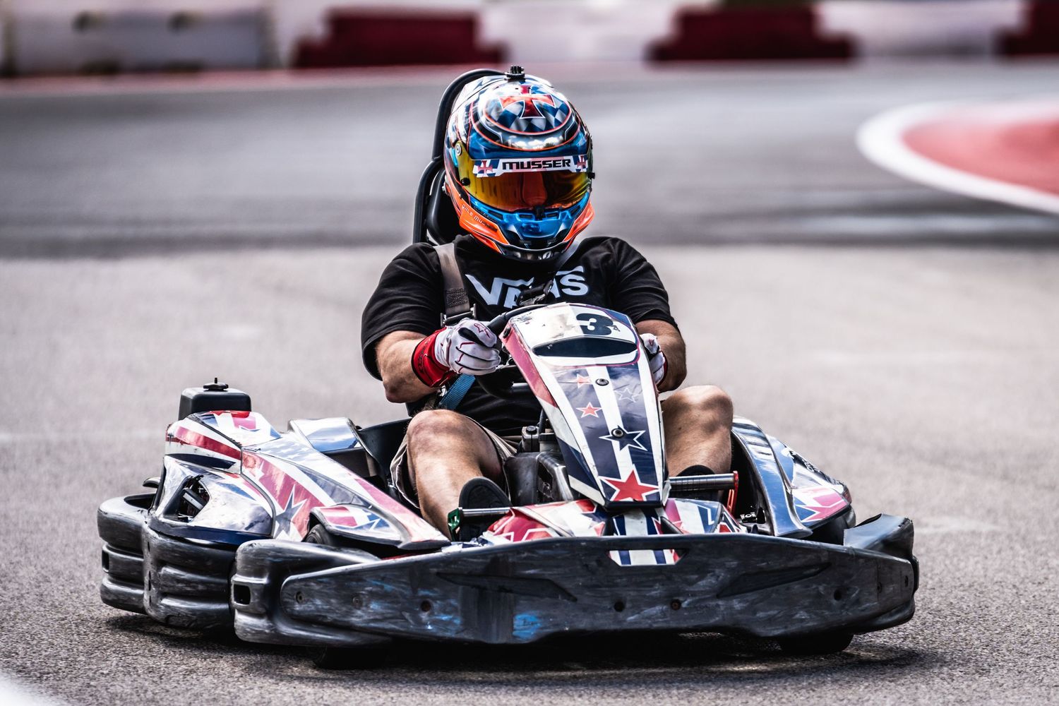 Go-kart driver taking a racing line through a corner on a professional circuit.