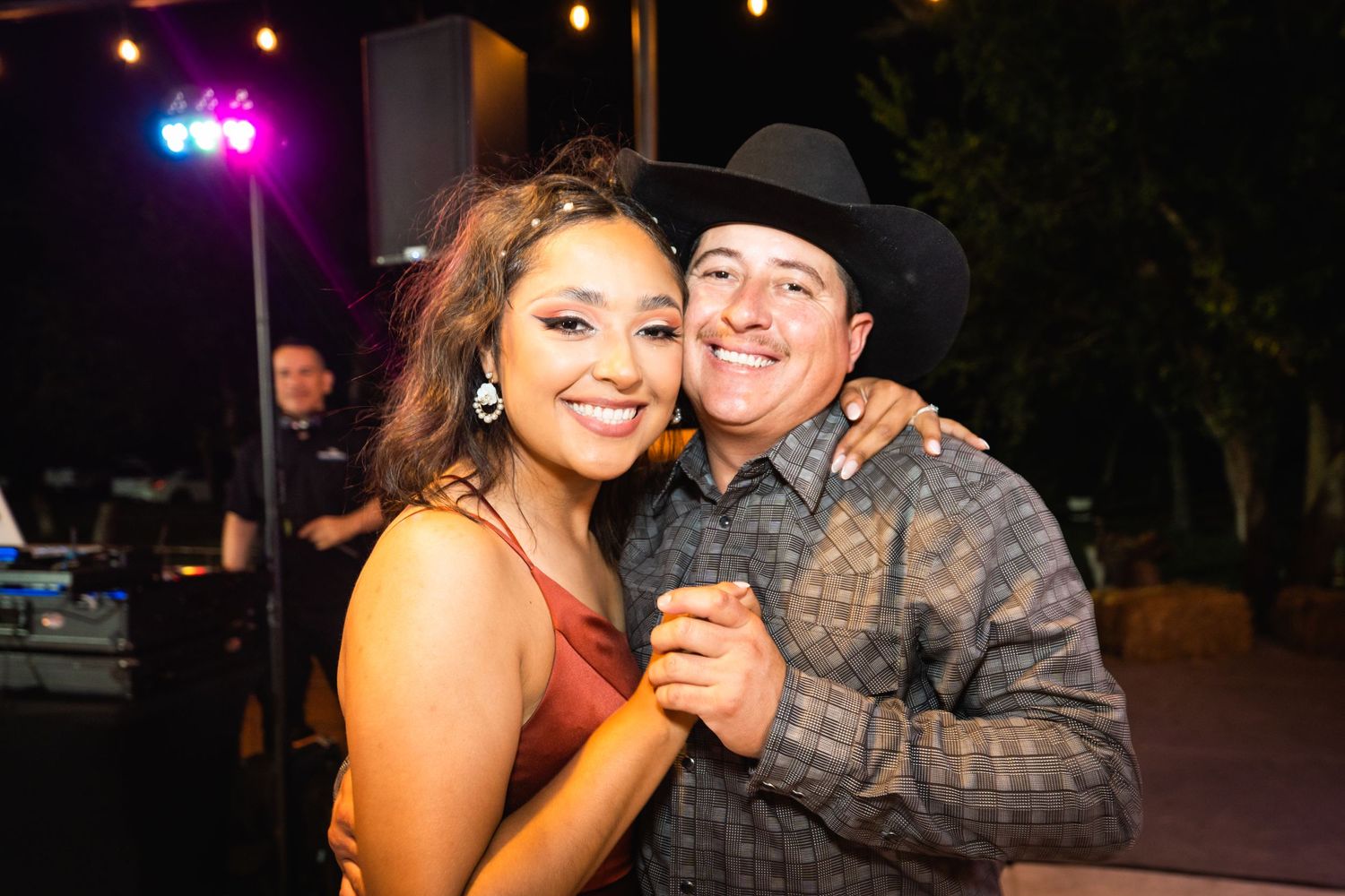 A couple sharing a dance moment at an outdoor evening reception with string lights.