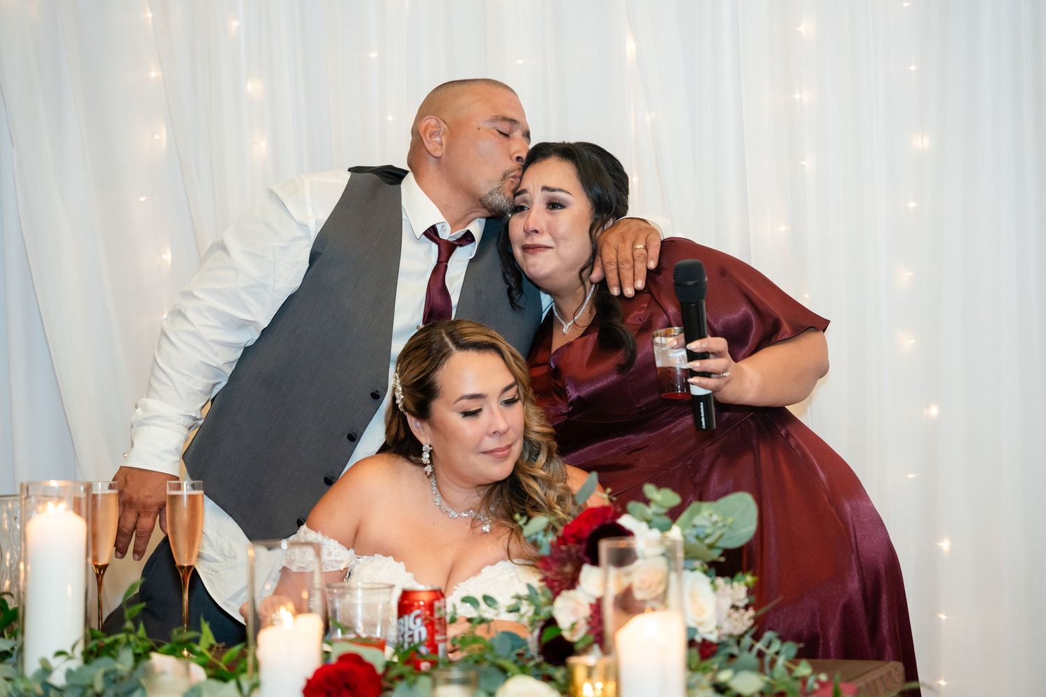 Wedding party members share an intimate moment at the decorated head table during reception.