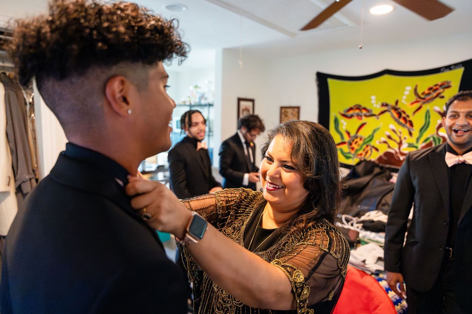 Wedding preparation moment with formal attire adjustments in bright indoor setting.
