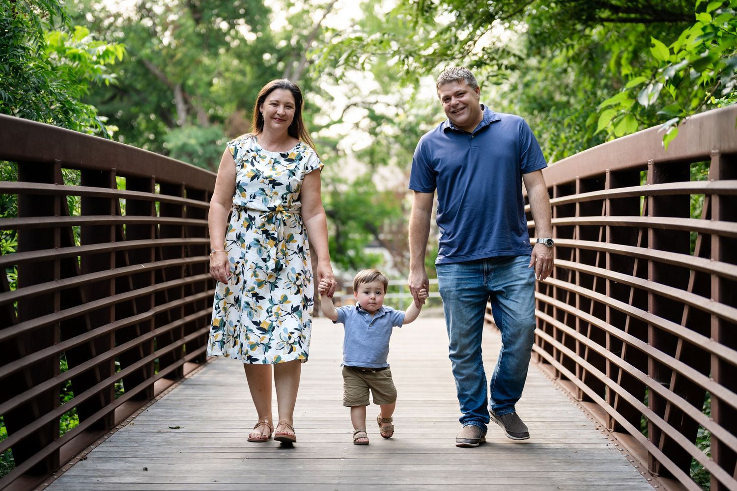 A family walking together on a wooden bridge during a summer photoshoot.