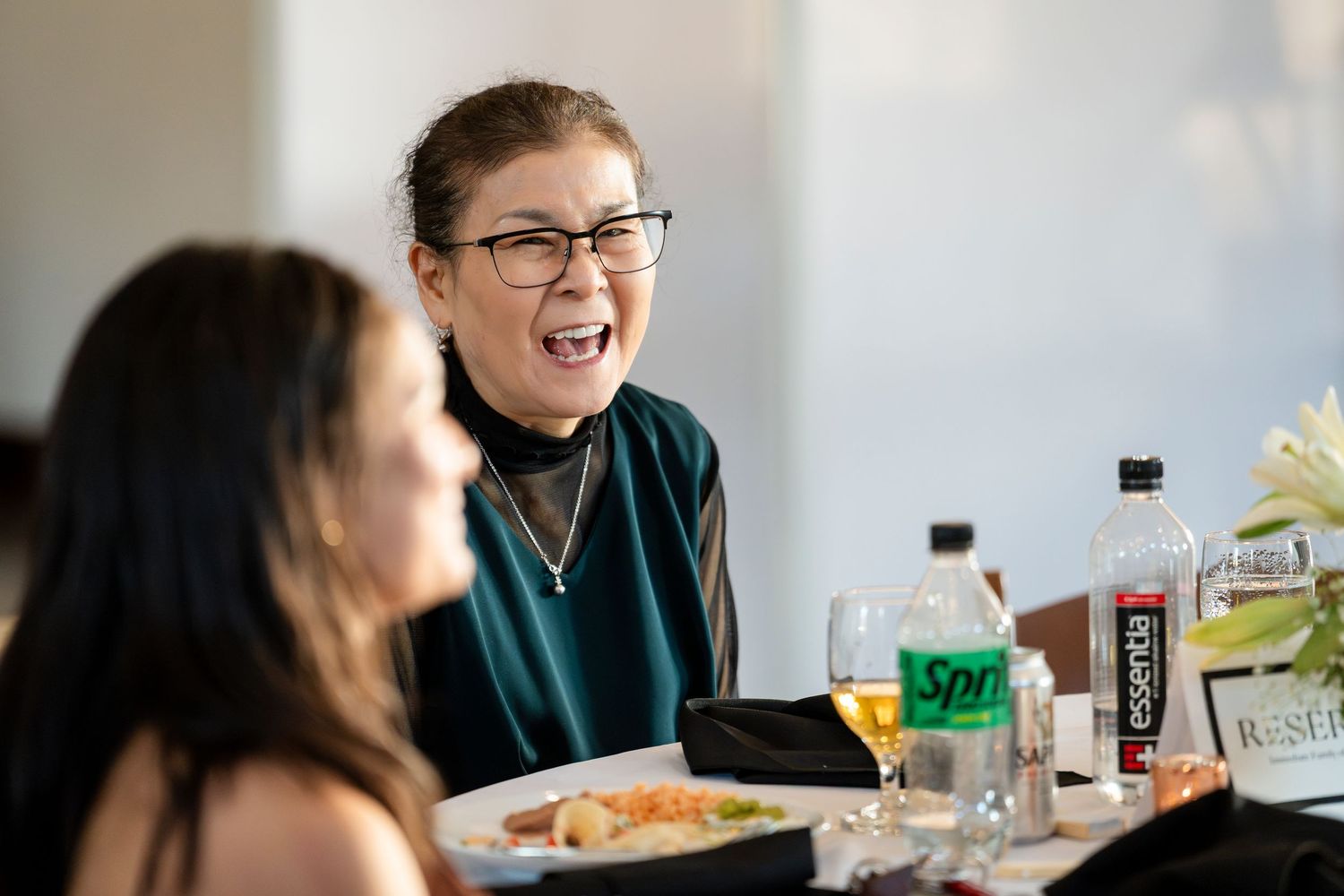 People seated at a casual dining table share conversation and laughter during a meal together.