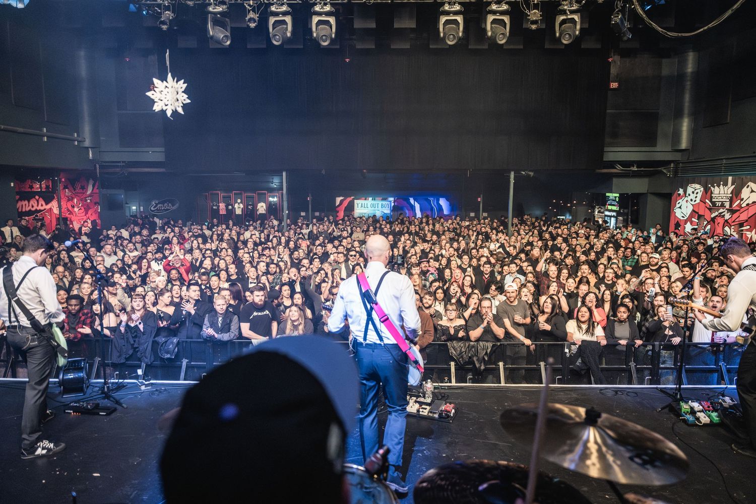 View from stage shows band performing for large crowd at concert venue.