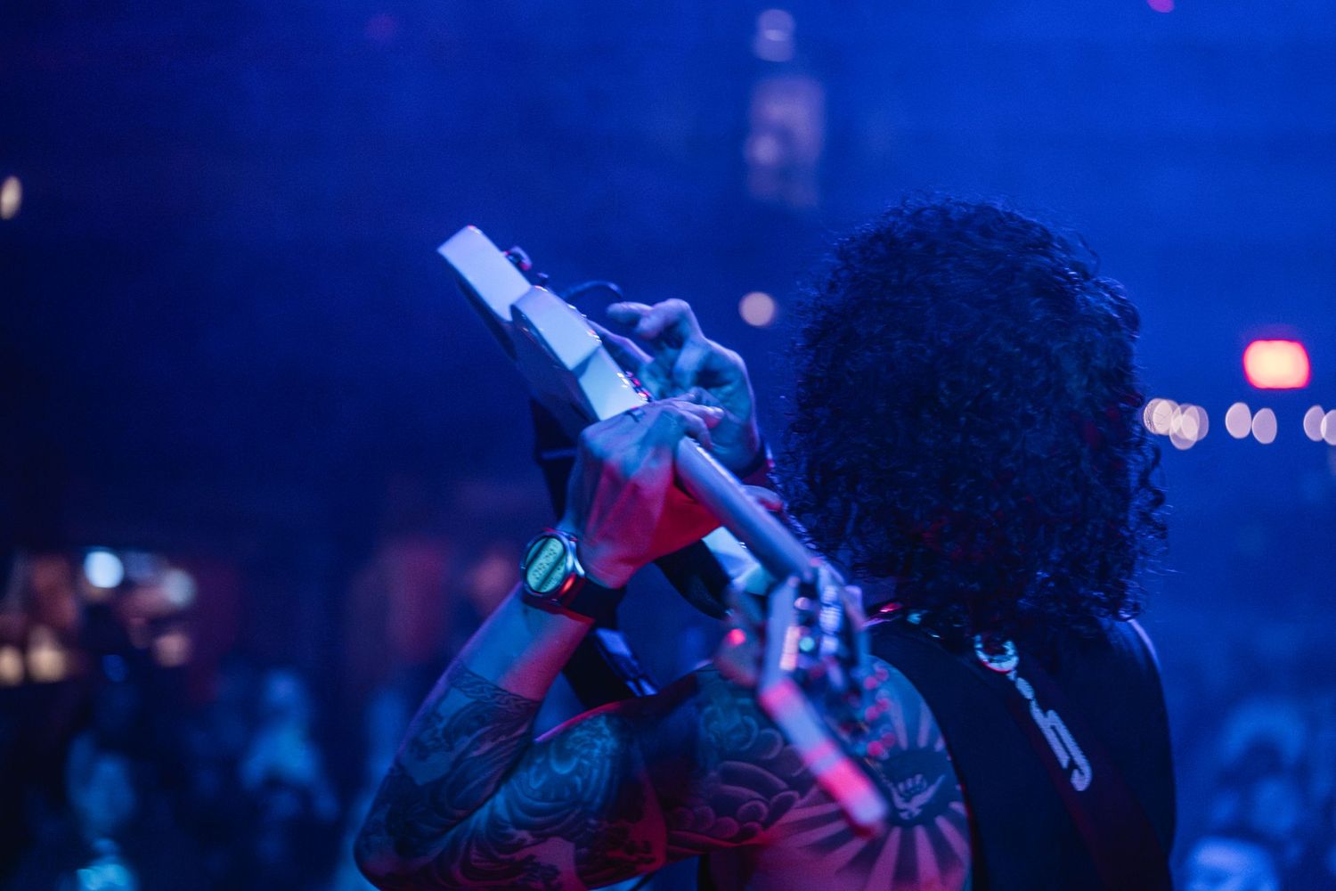 Silhouetted musician singing into microphone against blue atmospheric lighting.