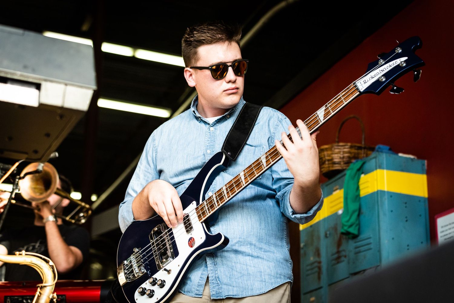 Musician plays bass guitar while performing at an indoor venue.