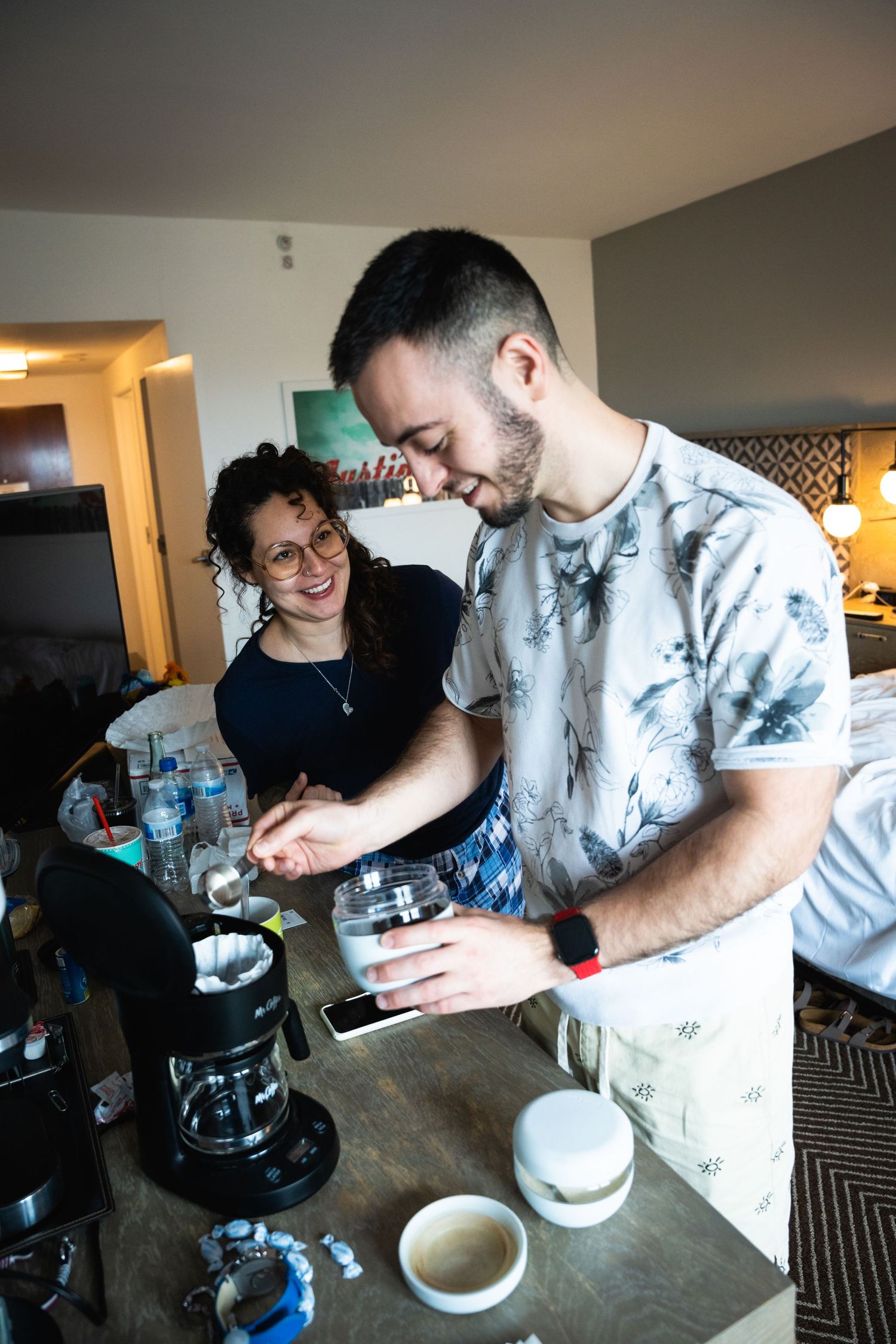 Two people making coffee together at a home coffee bar with various brewing equipment.