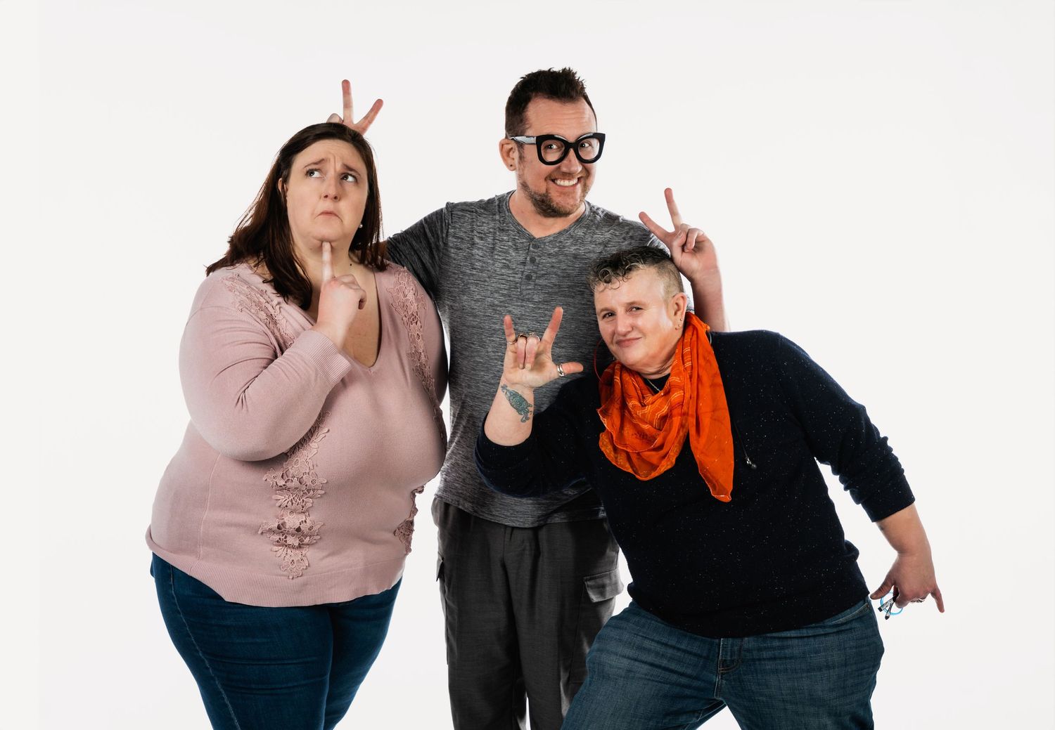 Three friends pose playfully together against a white background.