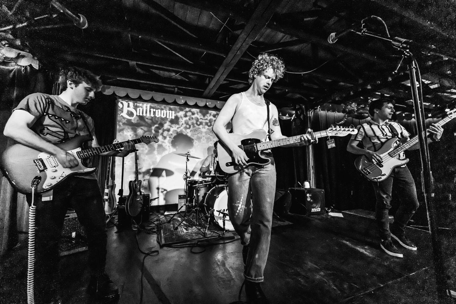 Black and white photo of musicians performing on stage with guitars.