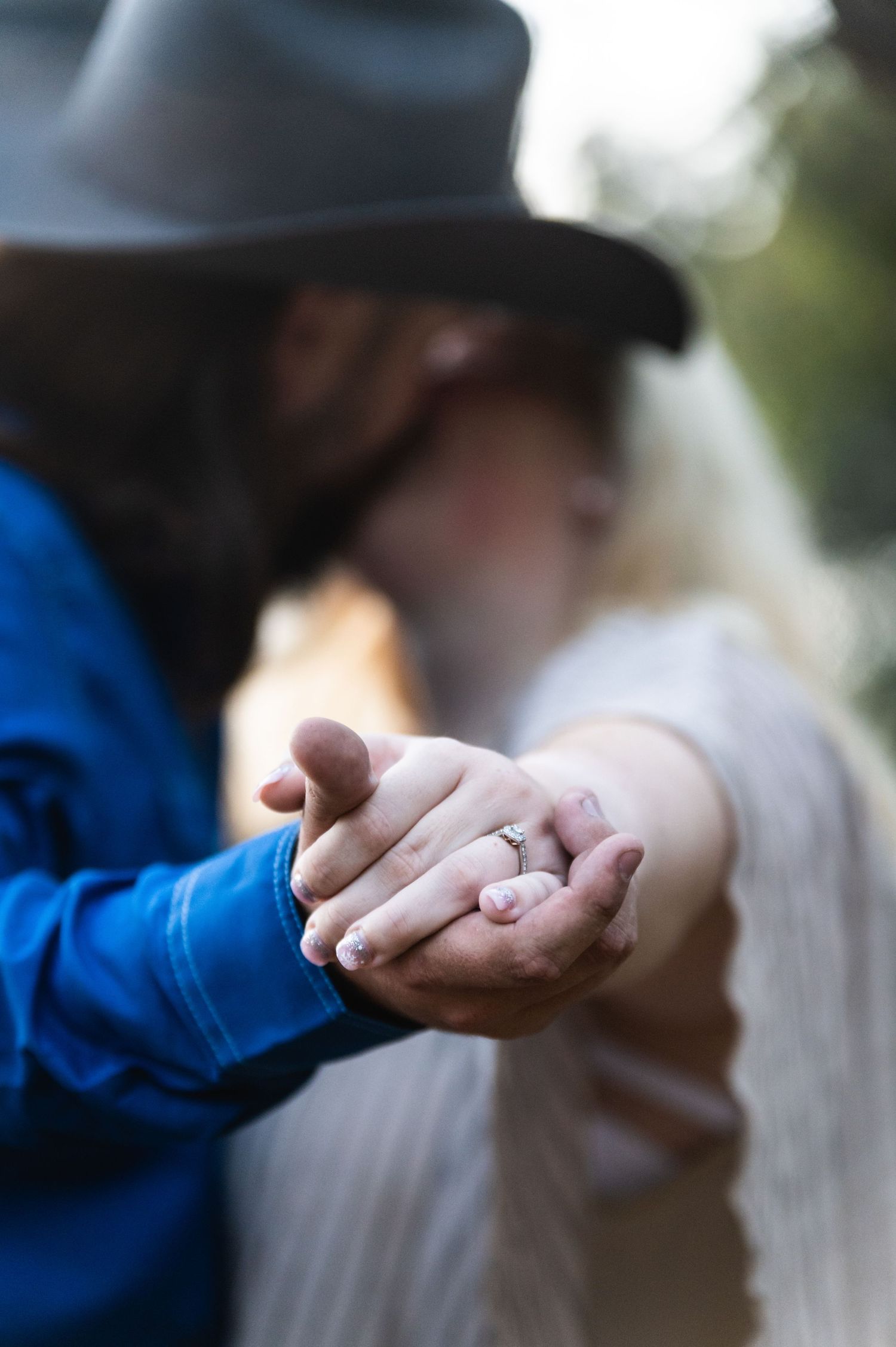Close-up of hands displaying an engagement ring during an outdoor photo shoot.
