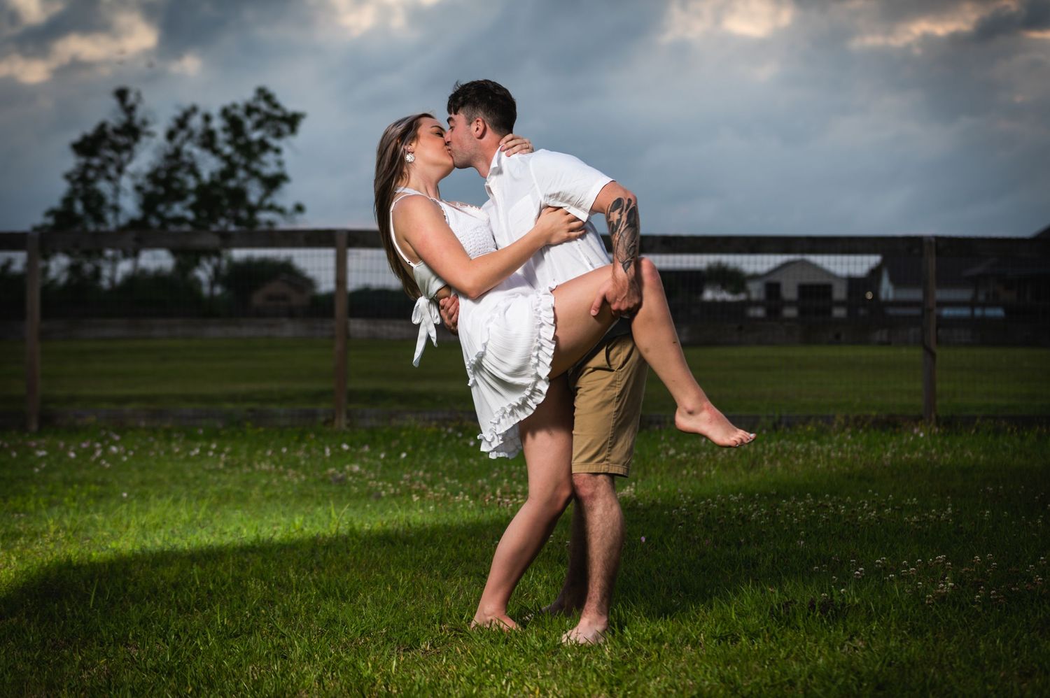 A romantic lift pose photographed in a field during sunset.