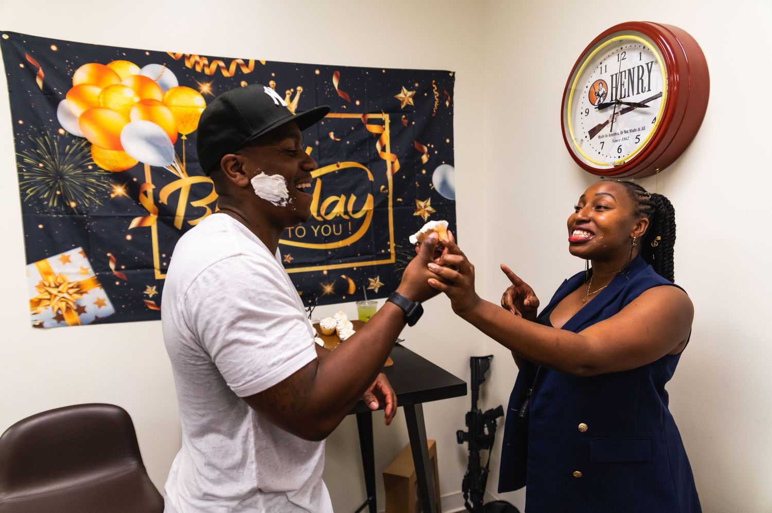 Two people sharing an excited moment in front of a birthday party backdrop.