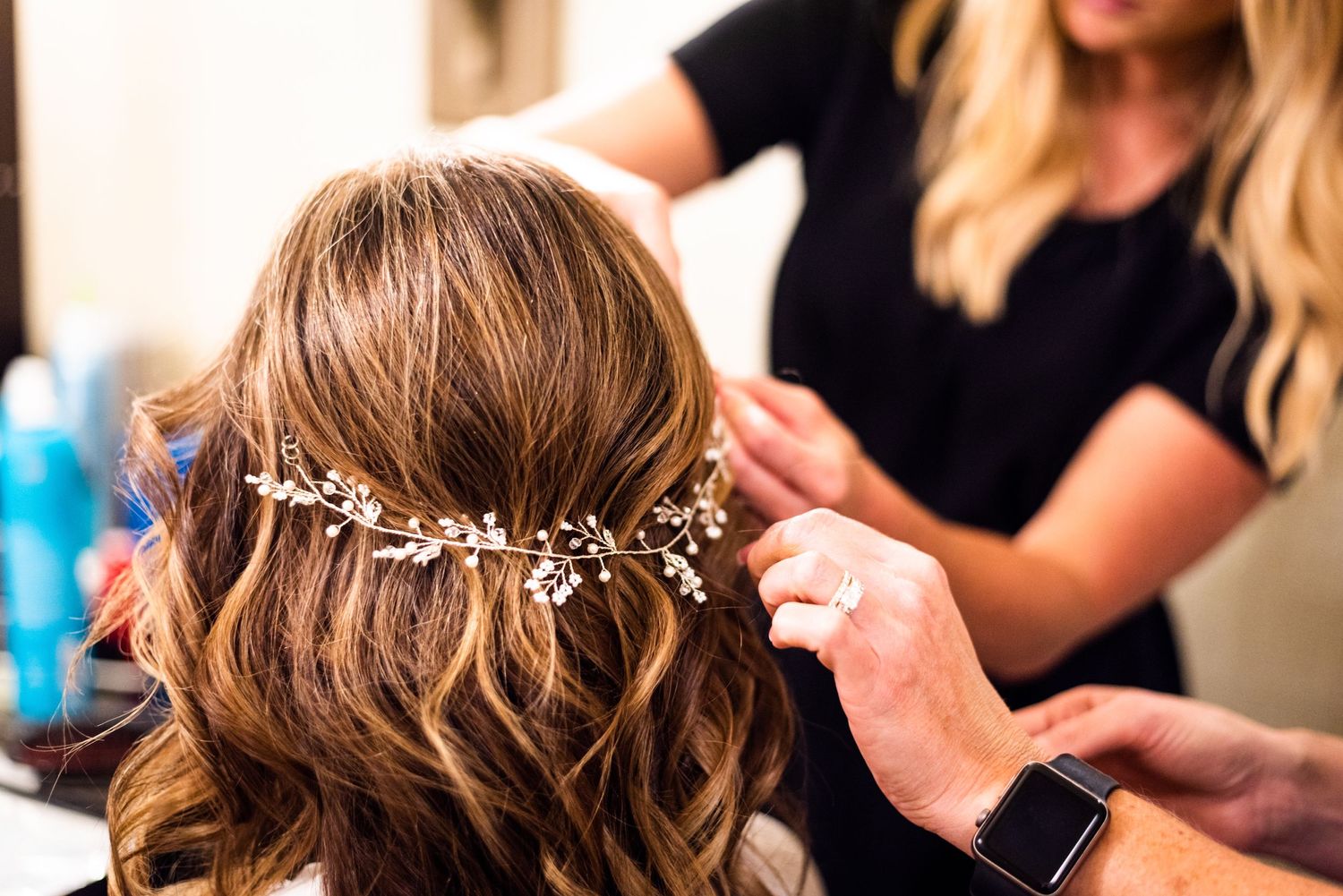 Delicate crystal hair accessory being placed in styled wavy brown hair.