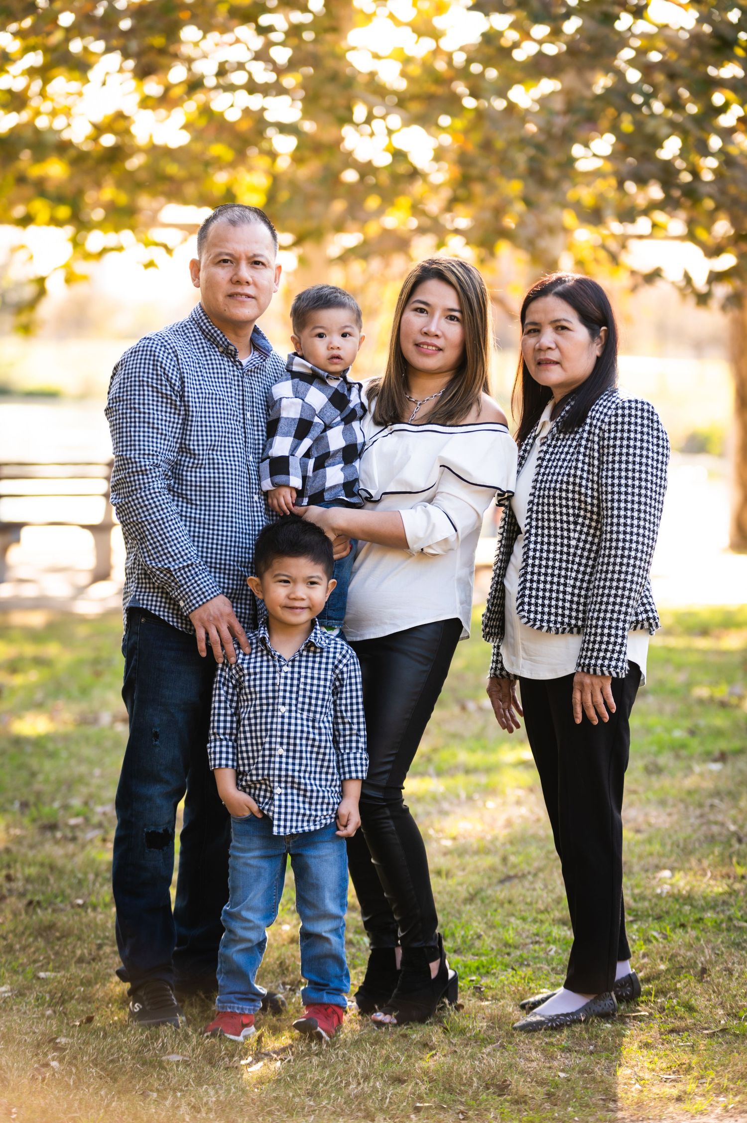 A family of five poses together for a portrait in a park during golden hour.