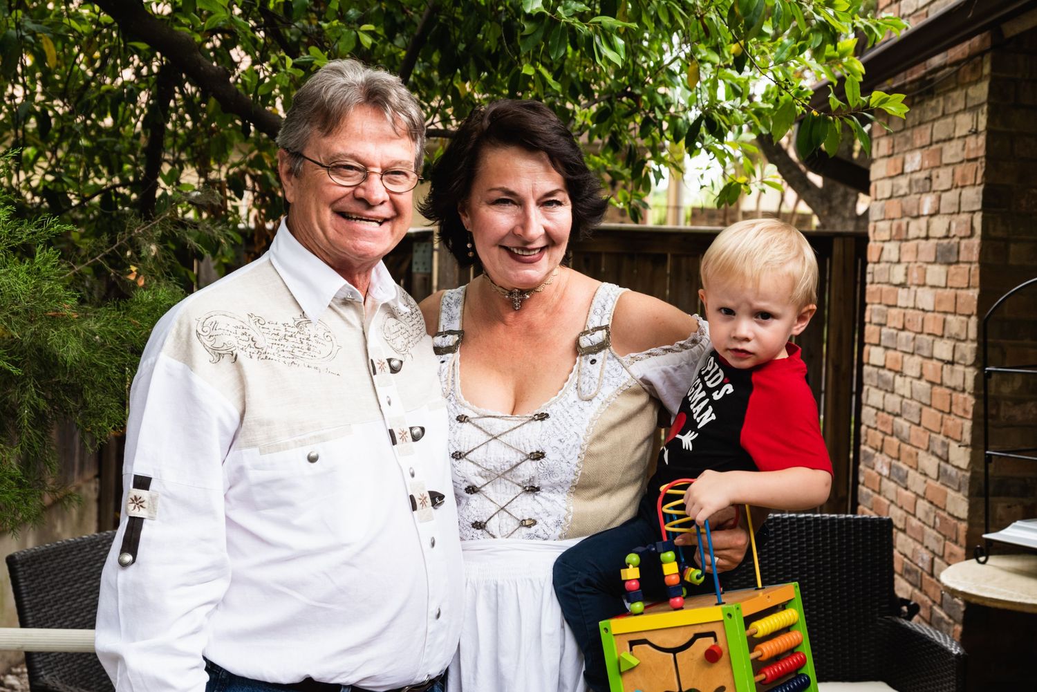 Outdoor family portrait with traditional dress and young child holding colorful gift.