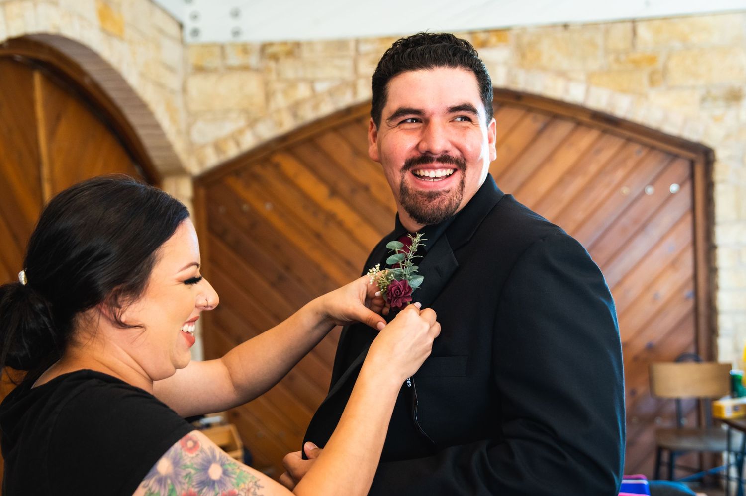 Two people share a joyful moment while adjusting formal attire.