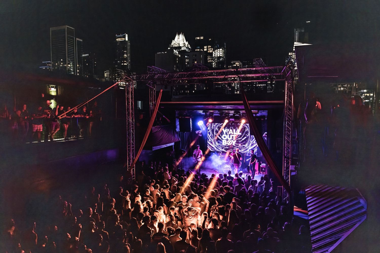 Night concert with purple lighting illuminating crowd and stage setup.
