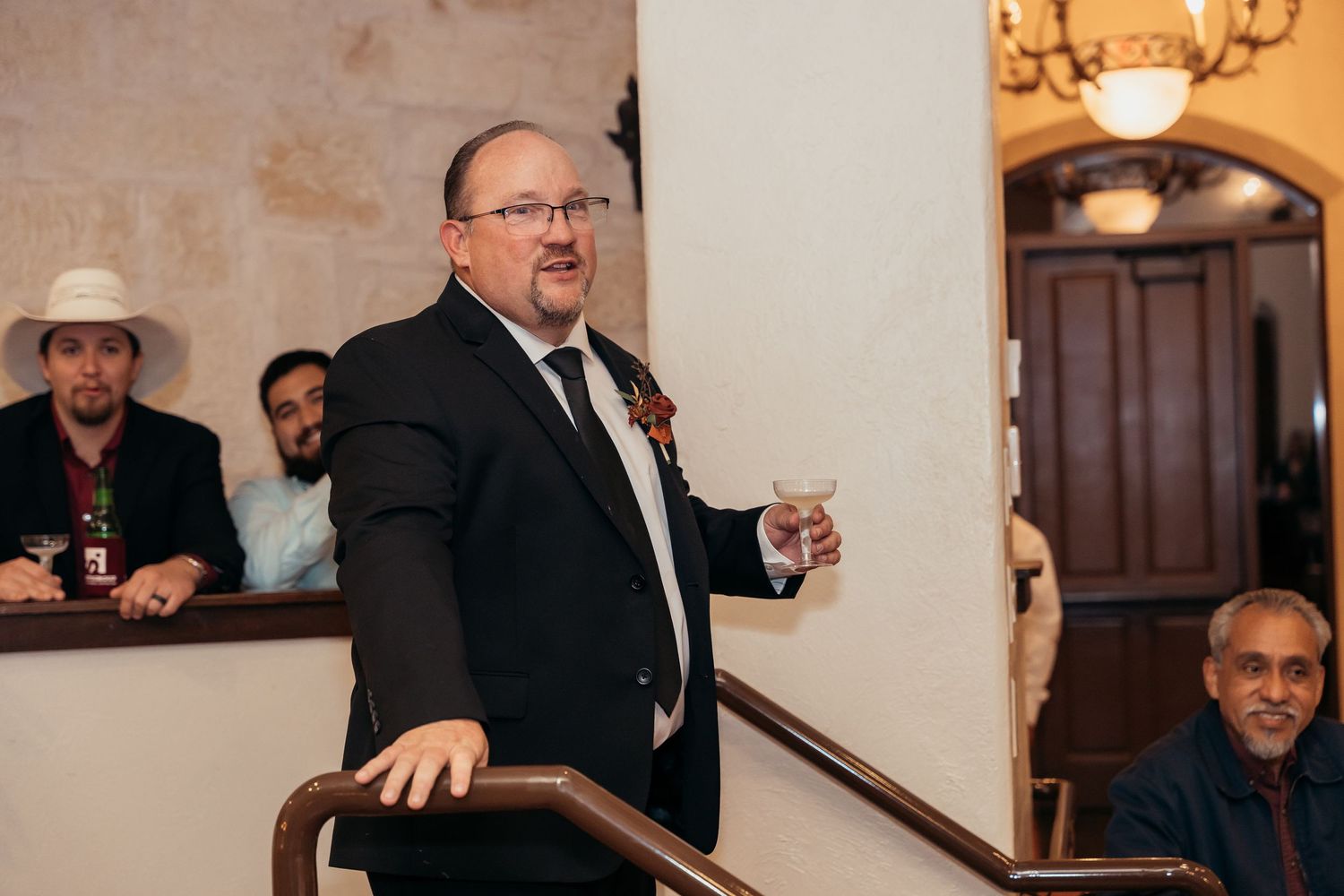 Guest delivers a speech during wedding reception while standing at railing.