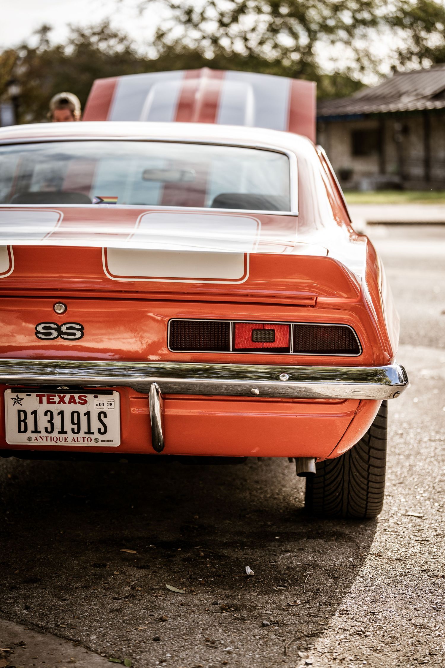 Rear view of a classic orange Chevrolet Camaro SS showing Texas license plate and distinctive taillights.