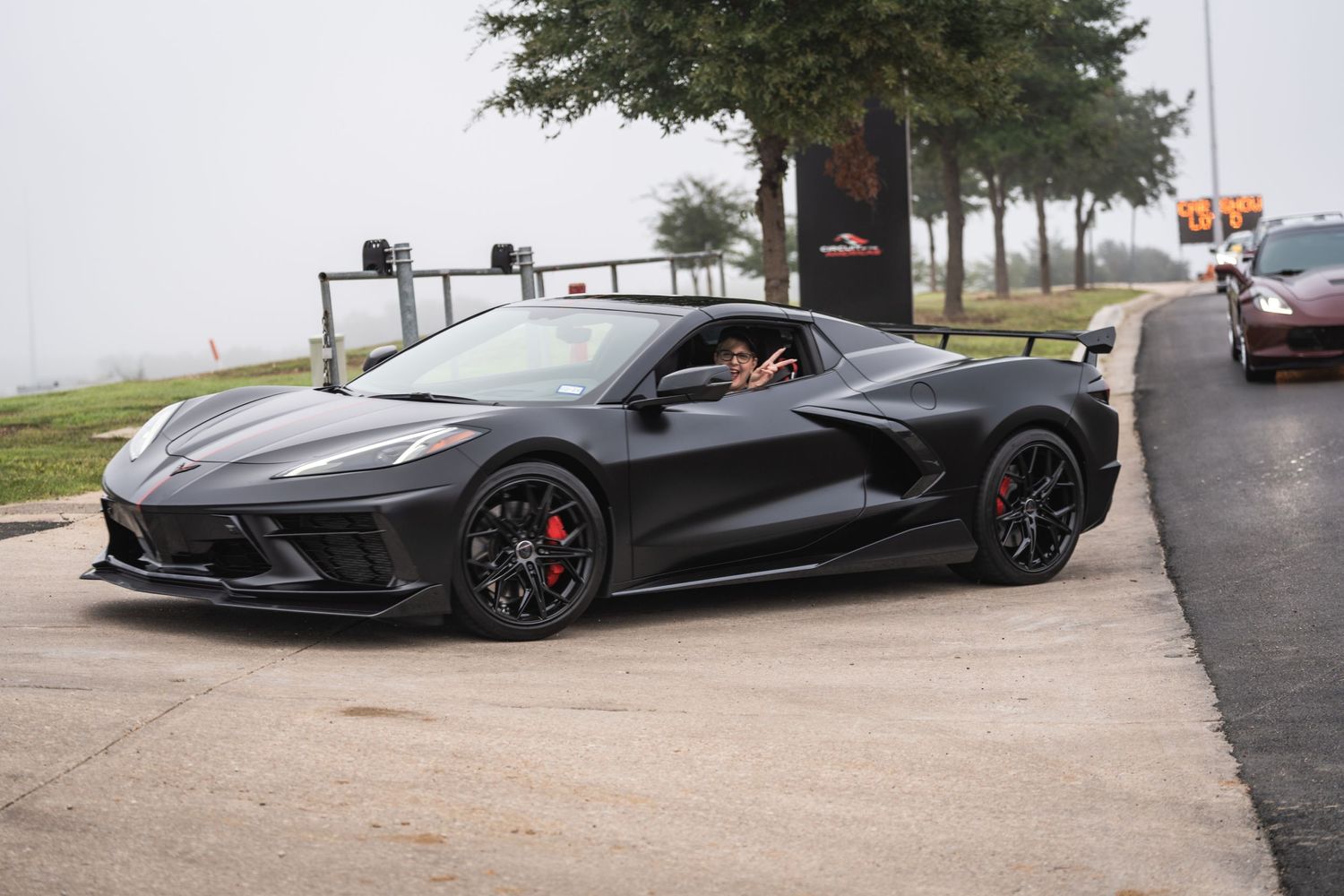 A sleek black Chevrolet Corvette C8 with aggressive styling parked on a curved road.