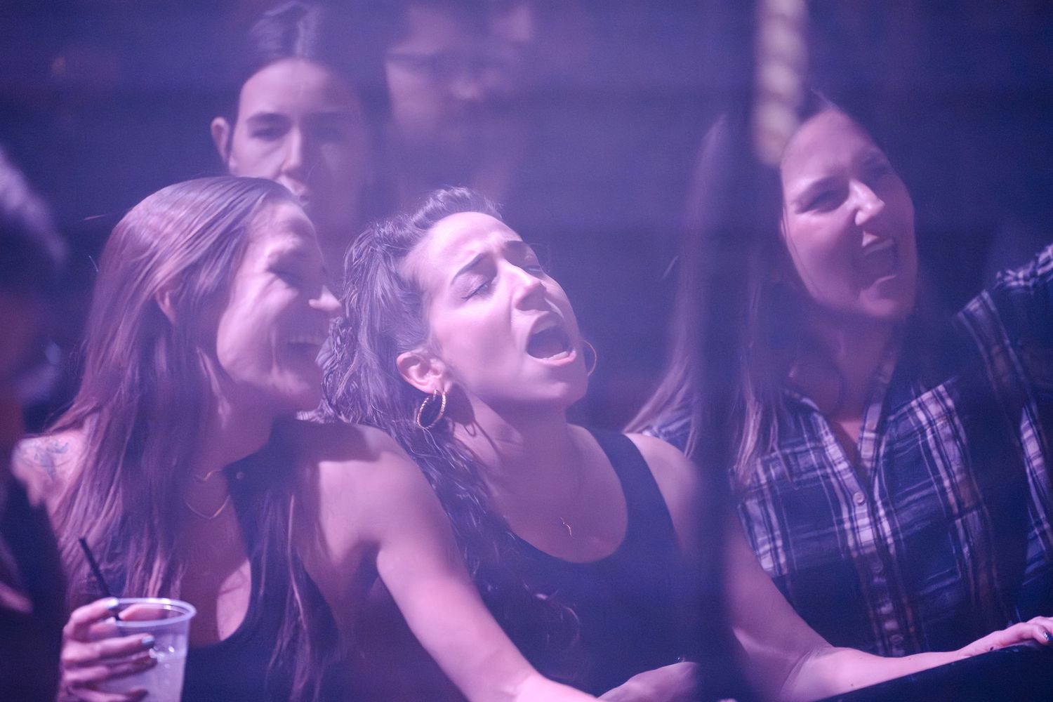 Music fans react enthusiastically to a performance under atmospheric purple venue lighting.