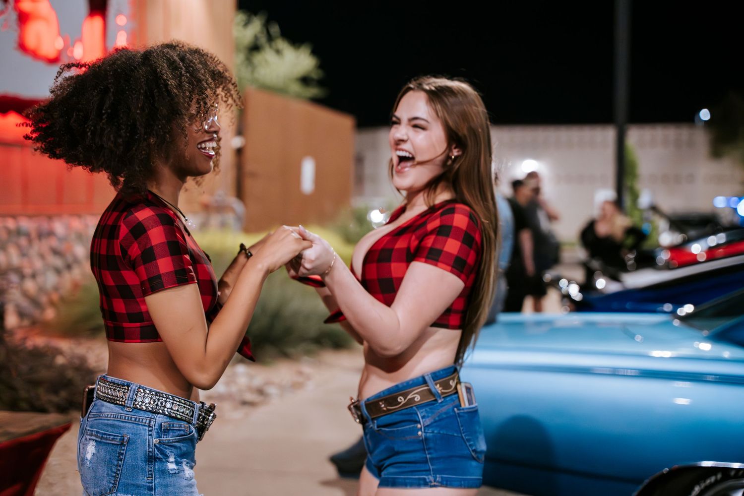 Two friends in matching plaid tops and jeans having fun together outside at night.