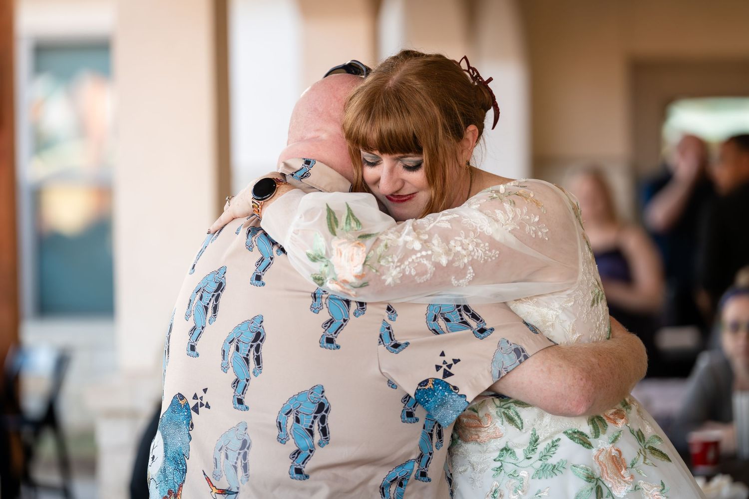 Couple in floral dress and suit share a romantic dance at a wedding reception.