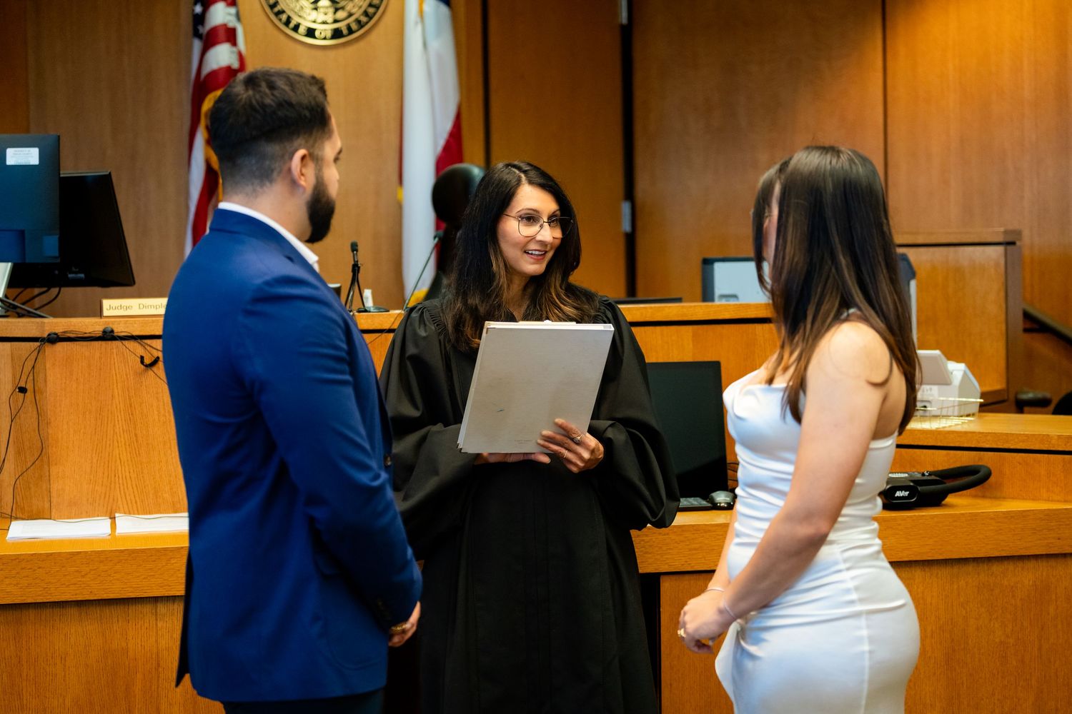 A couple stands before a judge in a courtroom during an intimate wedding ceremony.