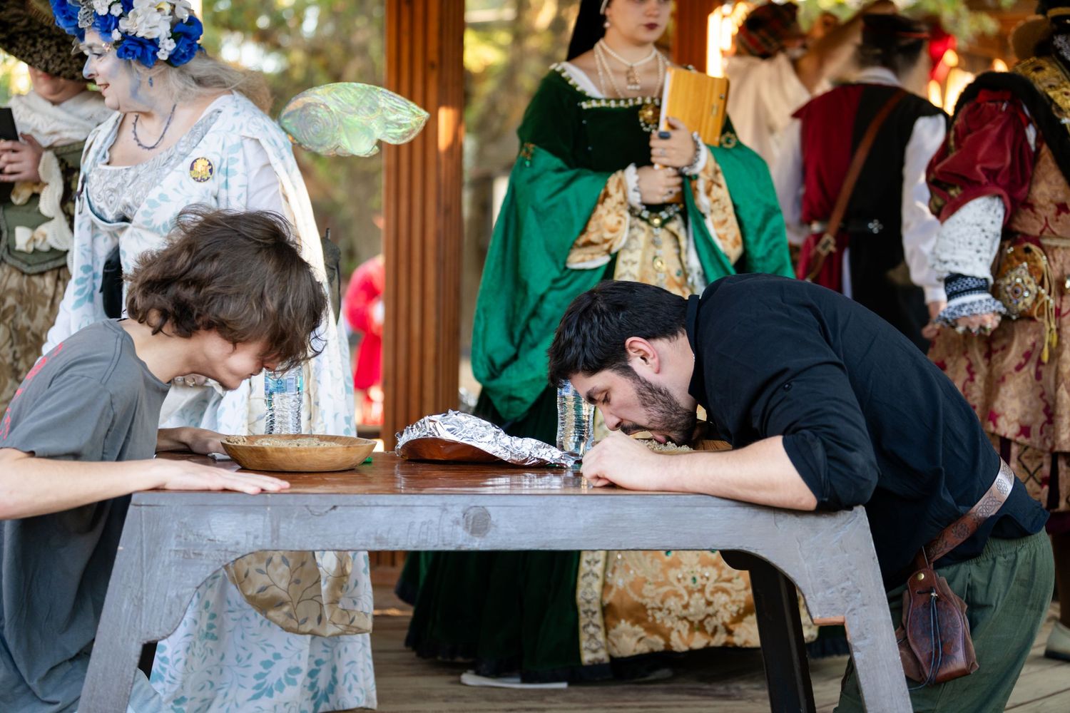 People signing a guest book at an outdoor wedding reception venue with wooden beams and decorative elements.